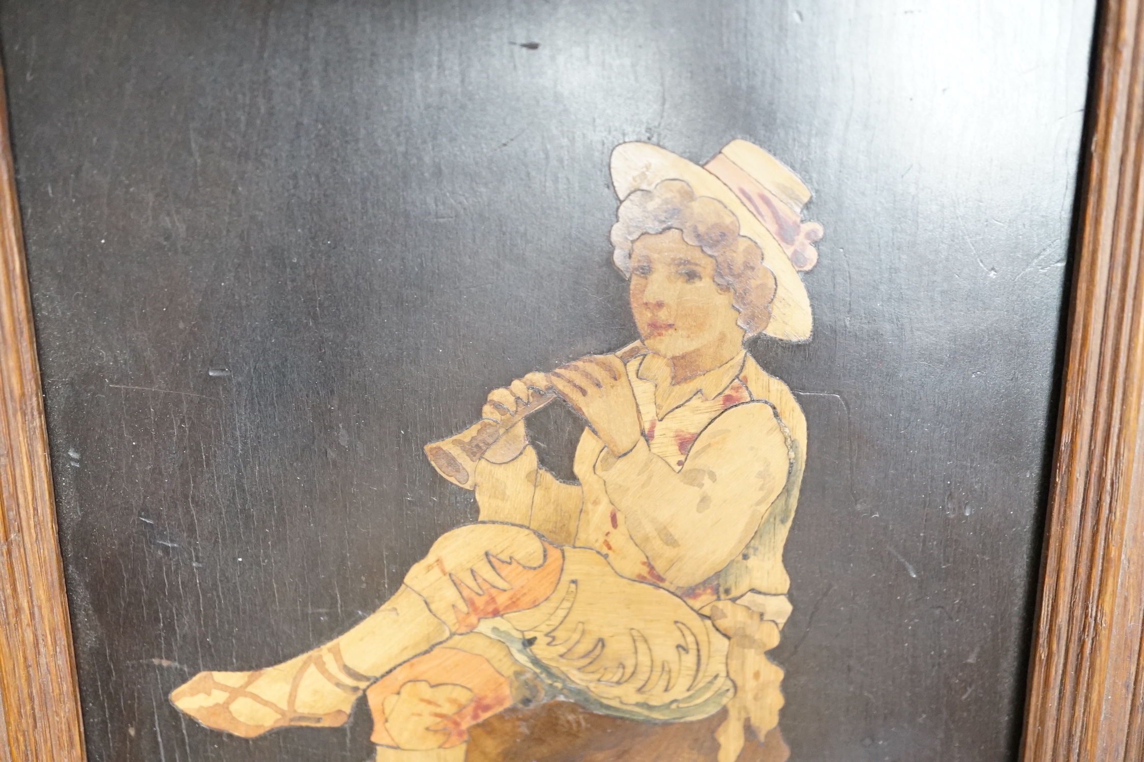 A Sorrentoware marquetry panel of a boy playing a flute, 14cm wide, 21.5cm high